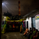 Residents of Patharripara neighborhood in Korba wait to resume religious festivities during a power outage, as the chimney of a coal power plant blows out smoke in the background. They were still waiting when we left the area half an hour later.